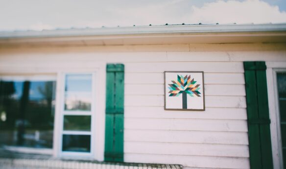 Barn quilt with tree decoration on white house