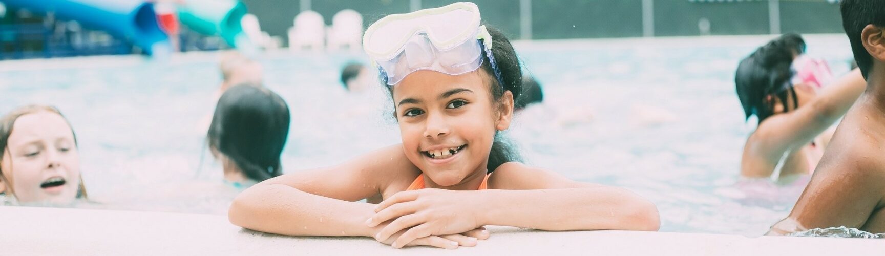 Child in pool with waterslide in background