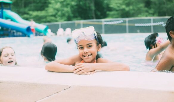 Child in pool with waterslide in background